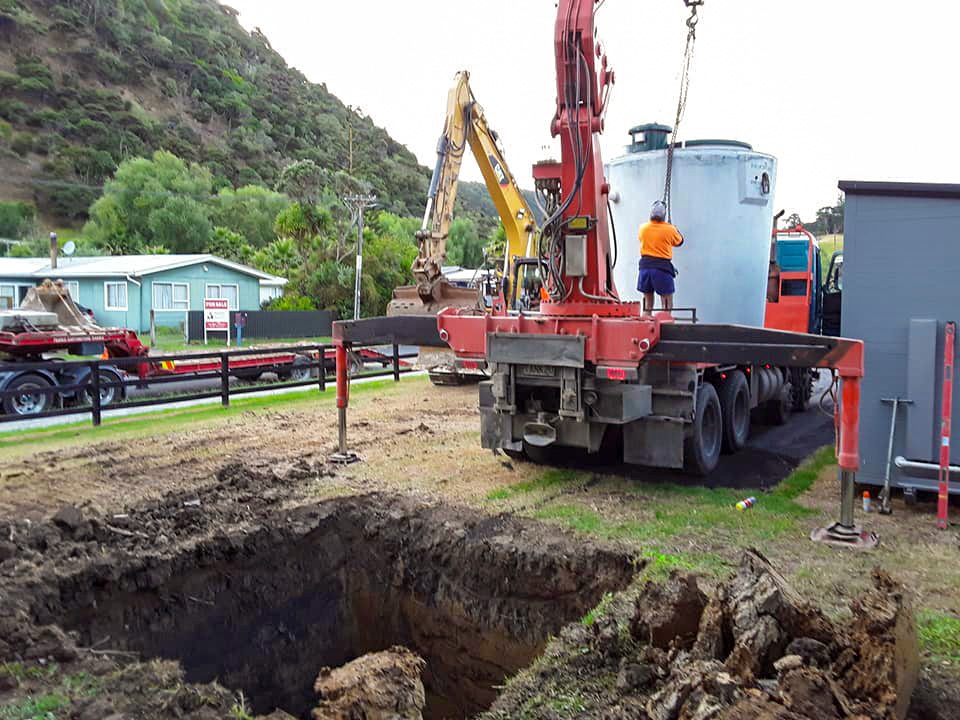 Crew installing large wastewater tank using crane truck